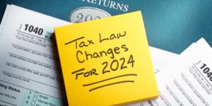 A yellow note pad rests on top of a 1040 tax form