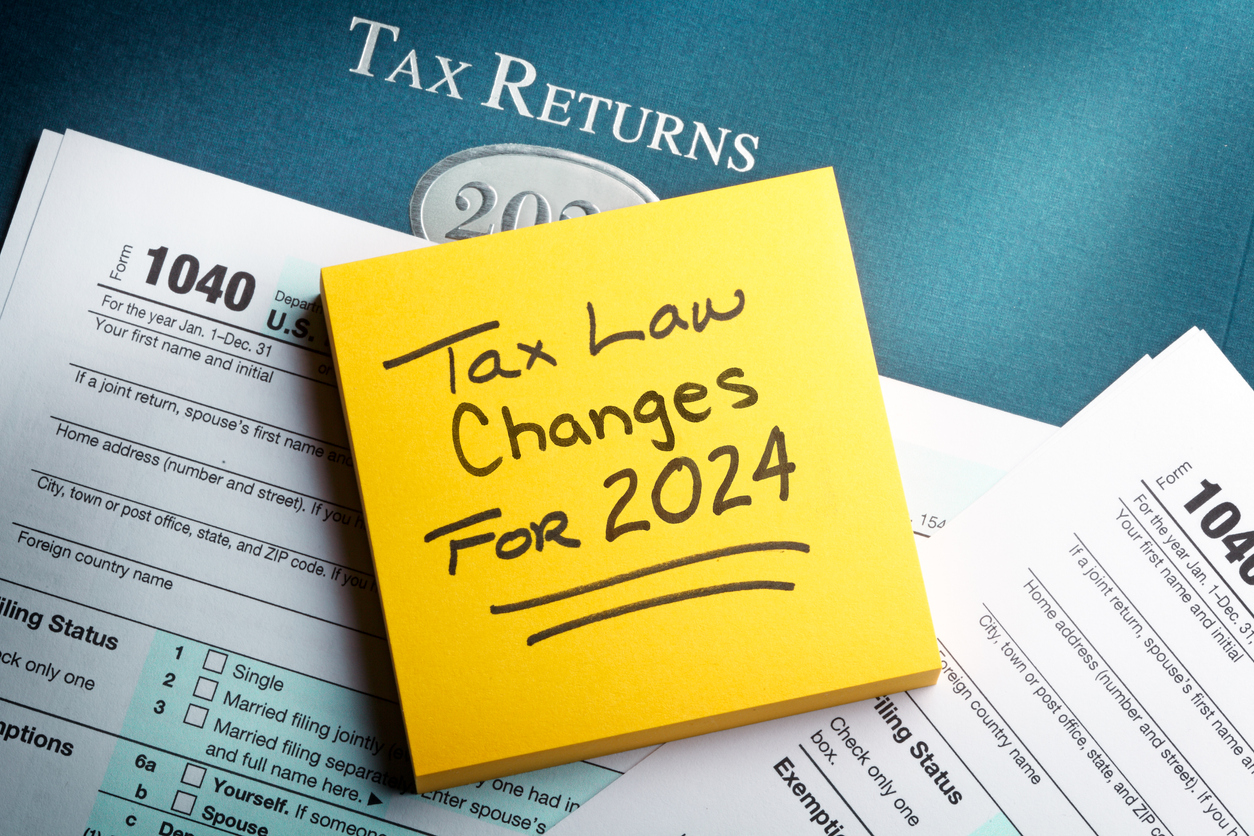 A yellow note pad rests on top of a 1040 tax form